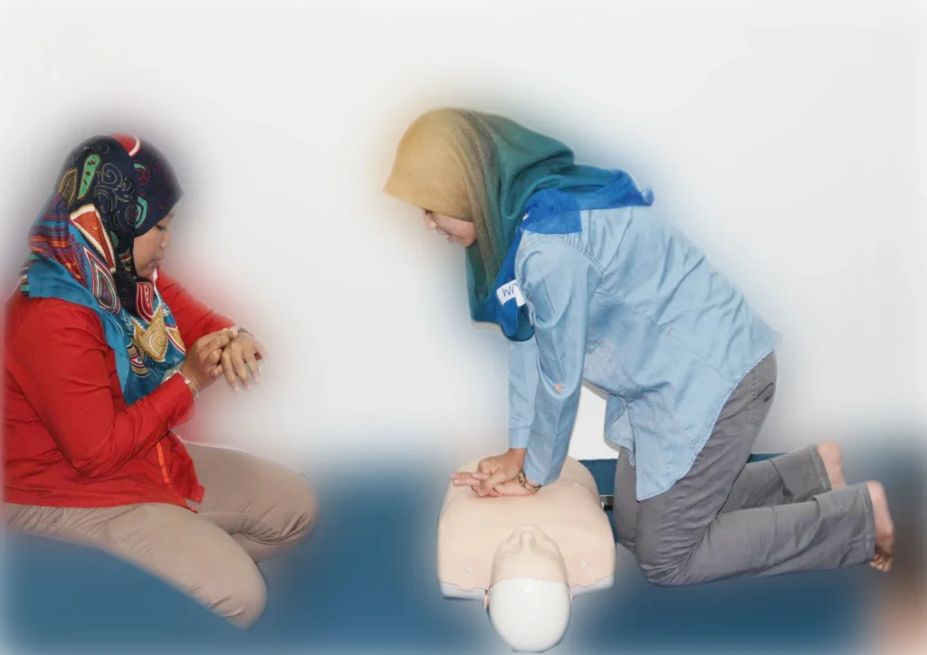 Two female participants performing CPR on a medical manikin during a practical first aid training course.